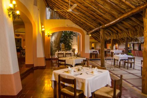 a restaurant with white tables and chairs in a room at Villas Arqueologicas Chichen Itza in Chichén-Itzá
