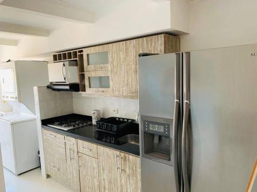La cuisine est équipée d'un réfrigérateur en acier inoxydable et de placards en bois. dans l'établissement Grafiti Love, à Sabaneta