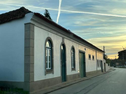 a white building with green doors on a street at AVEIRO MAIAS VILLAGE - CASA DO ÁLVARO in Oliveirinha