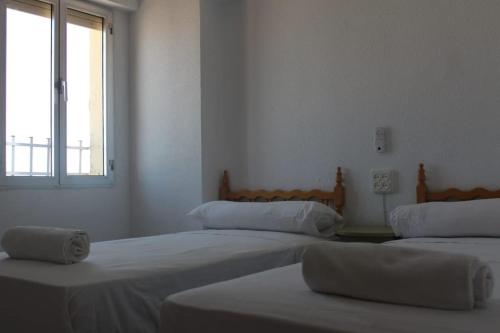 two beds in a white room with a window at ROCH2 - Modern Apartment near Metro in Seville