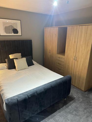 a bedroom with a large bed and wooden cabinets at La mansion in Wednesbury
