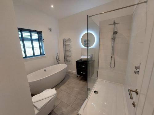 a white bathroom with a tub and a shower at Apple Lodge in Bovey Tracey