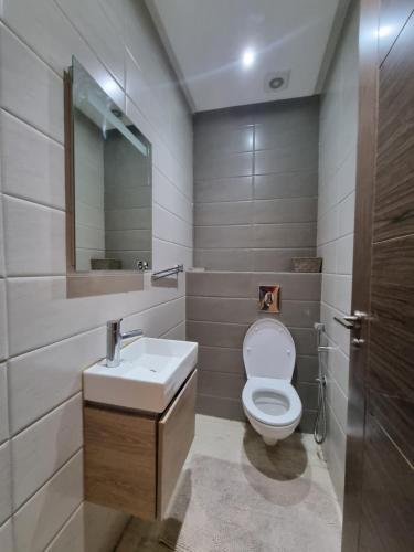 een badkamer met een toilet, een wastafel en een spiegel bij L3 avec piscine in Agadir