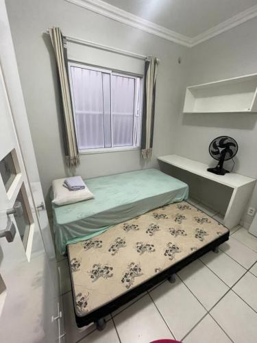 Cette petite chambre comprend 2 lits et une fenêtre. dans l'établissement Apartamento próximo ao aeroporto, à Fortaleza