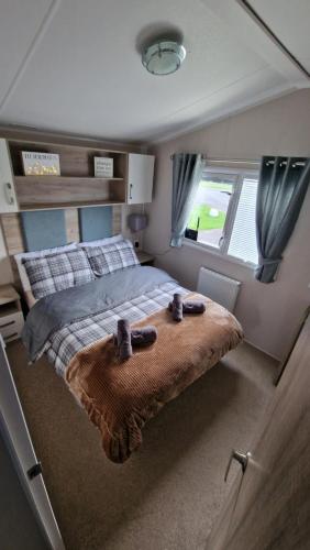 un dormitorio con una cama con dos animales de peluche en Seaside Heaven - Southerness Caravan Rental en Mainsriddle