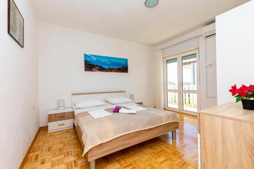 a white bedroom with a bed and a window at Apartment Jele in Omiš