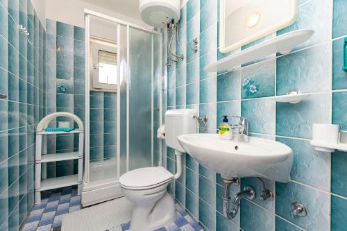 a blue tiled bathroom with a toilet and a sink at Apartment Jele in Omiš