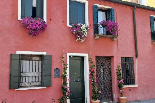 a red building with flowers and a door and windows at Storico alloggio fronte piazza in Borgo Portello in Padova