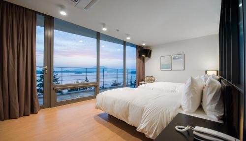 ein Schlafzimmer mit einem großen Bett und einem großen Fenster in der Unterkunft Vigo Resort in Yeosu