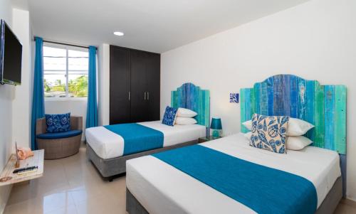 a hotel room with two beds and a television at White Coral ApartaSuites in San Andrés