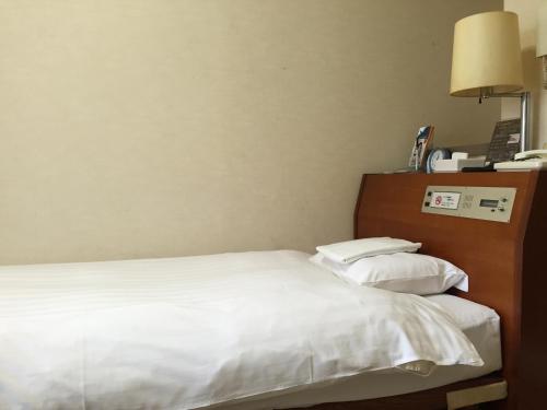 a hotel room with a bed and a lamp at Sky Heart Hotel Kawasaki in Kawasaki