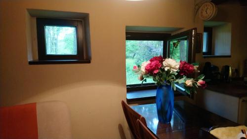 Błękitna waza pełna kwiatów siedząca na stole w obiekcie Stone cottage 