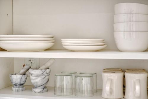 a shelf filled with white bowls and plates at The Ledger Residences by Sosuite - Old City in Philadelphia