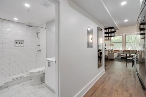 a white bathroom with a toilet and a hallway at The Ledger Residences by Sosuite - Old City in Philadelphia