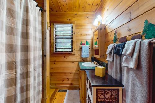 a bathroom with wooden walls and a sink and a mirror at Sleepy Bear Hideaway in Mineral Bluff