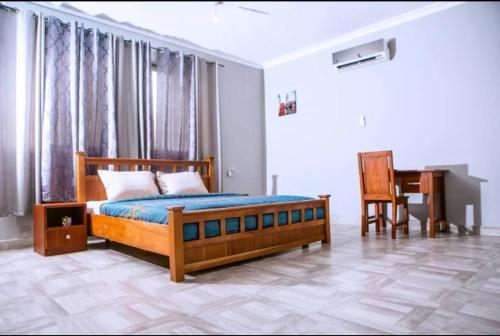 Schlafzimmer mit einem Bett, einem Schreibtisch und einem Stuhl in der Unterkunft Home from Home GuestHouse in Accra