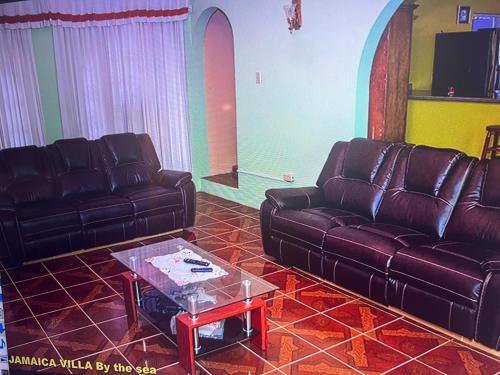 a living room with two leather couches and a coffee table at Jamaica Villa By The Sea in St Mary