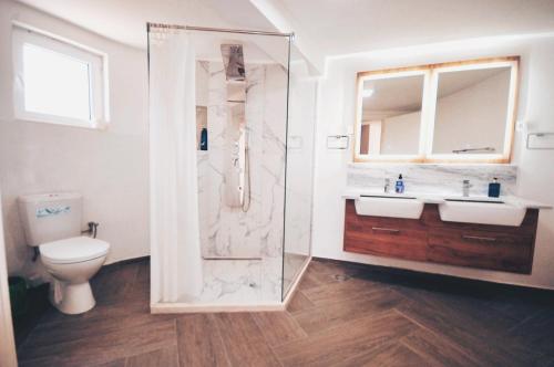 a bathroom with a shower and two sinks and a toilet at Villa Redzic Residence in Brca