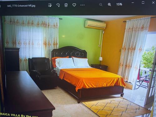 1 dormitorio con 1 cama con manta naranja en Jamaica Villa By The Sea, en Saint Mary