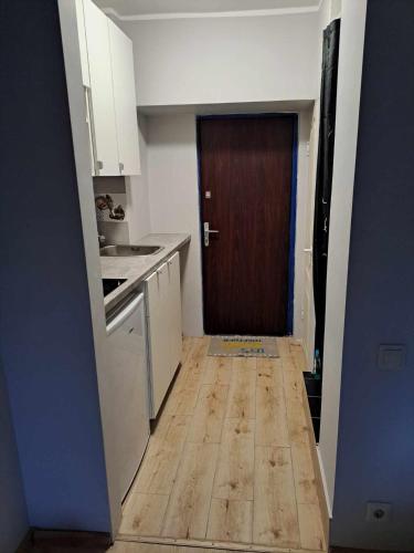 a kitchen with a wooden floor and a brown door at Small studio beween the Old Town and the airport in Rīga