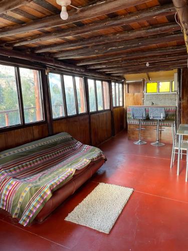 a bed sitting in the middle of a room with windows at Ecolodge las tunas in Cusco