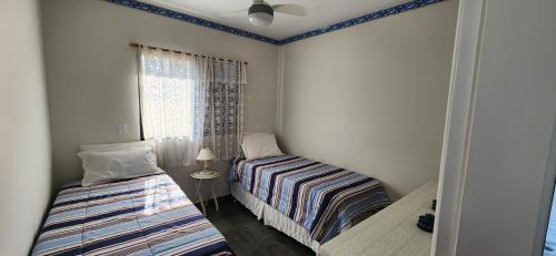 two beds in a small room with a window at SAN REMO in Guarujá