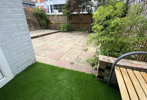 a yard with a bench and grass and a fence at Redhill Town Centre Garden Flat in Redhill