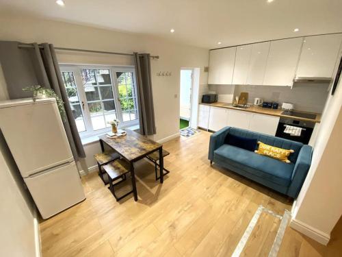 a living room with a blue couch and a table at Redhill Town Centre Garden Flat in Redhill