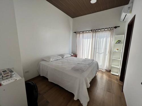 a white bedroom with a bed and a window at Mar adentro a tu alcance! in Santa Cruz de la Sierra