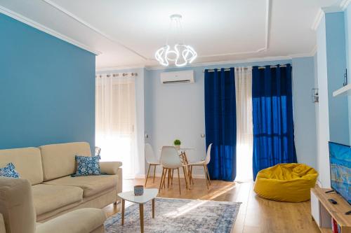een woonkamer met blauwe gordijnen en een bank bij Cane Apartment New Bazaar in Tirana