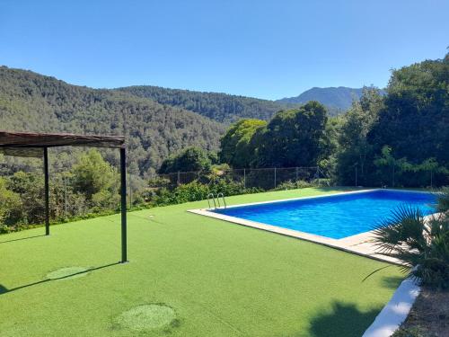 einen Pool mit grünem Rasen und Bergen im Hintergrund in der Unterkunft Casa rural La Senyora in Veo