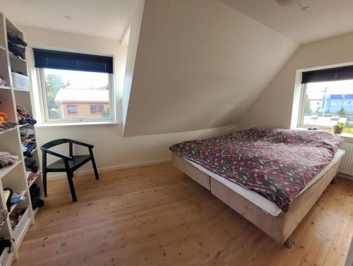 a bedroom with a bed and two windows at Skønt hus - tæt på Givskud Zoo og Legoland in Give