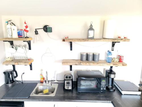 a kitchen counter with a sink and shelves on the wall at Cozy Private Suite in Winnipeg