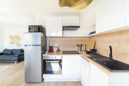 une cuisine avec des armoires blanches et un réfrigérateur en acier inoxydable dans l'établissement Le Cocon Margnolles - Caluire Croix Rousse, à Caluire-et-Cuire