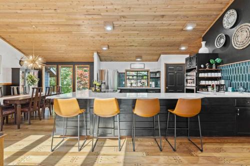 a kitchen with a large island with orange bar stools at Luxe Lake Home Reflect Recharge and Reconnect in Nine Mile Falls