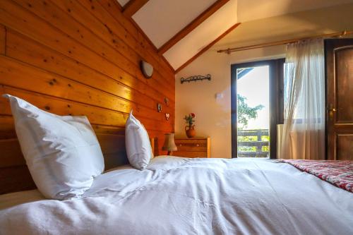 a bedroom with a large white bed with a wooden wall at Mountain Family Chalet on Prahova Valley in Comarnic