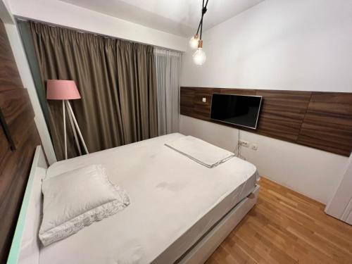 - une chambre avec un lit et une télévision à écran plat dans l'établissement Lusso Apartment, à Skopje