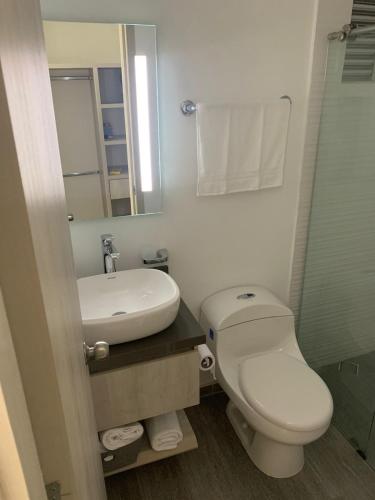 uma casa de banho com um WC, um lavatório e um espelho. em Hermoso y acogedor apartamento em Dosquebradas