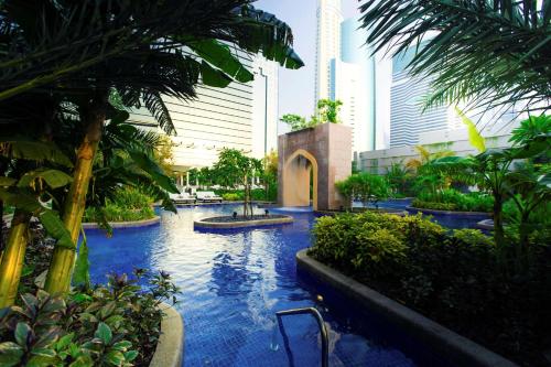 una piscina en un complejo con palmeras y edificios en Conrad Dubai, en Dubái