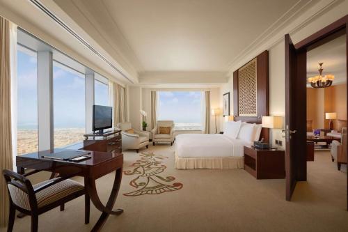 a hotel room with a bed and a desk and a television at Conrad Dubai in Dubai