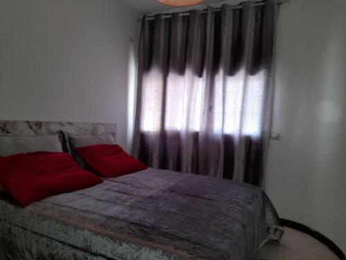 - une chambre avec un lit doté d'oreillers rouges et une fenêtre dans l'établissement superbe appartement bien placé, à Fès