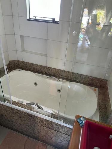 a bath tub in a bathroom with a glass wall at Pousada Chalé Suiço Bombinhas in Bombinhas