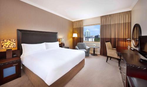 um quarto de hotel com uma cama grande e uma secretária em Hilton Sandton em Joanesburgo