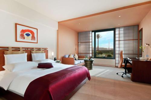 a large bedroom with a large bed and a desk at Hilton Kuwait Resort in Kuwait