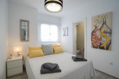 1 dormitorio blanco con 1 cama grande con almohadas amarillas en Rooftop sea view with Jacuzzi and A/C, en Puerto del Carmen