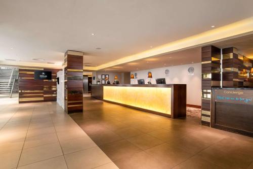 a hotel lobby with a reception desk and shelves at Hilton London Olympia in London