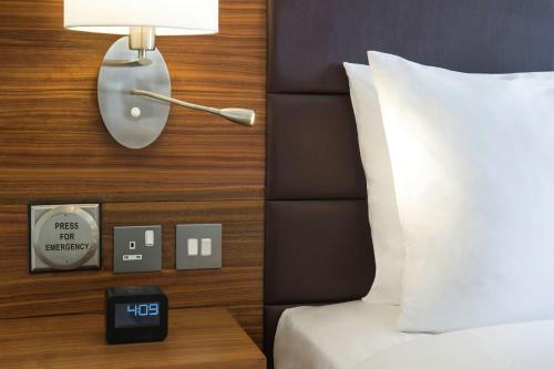 a hotel room with a bed and a lamp and a clock at Hilton Garden Inn Ras Al Khaimah in Ras al Khaimah