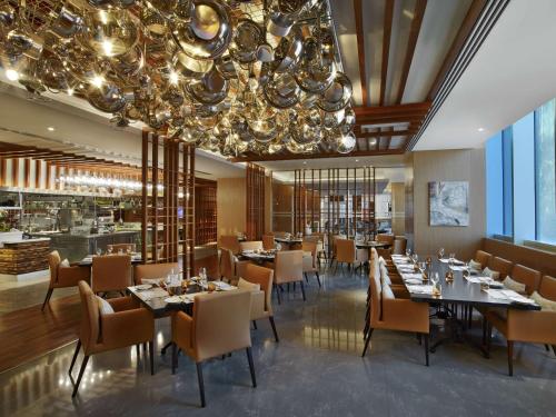 a dining room with tables and chairs and a chandelier at V Hotel Dubai, Curio Collection by Hilton in Dubai