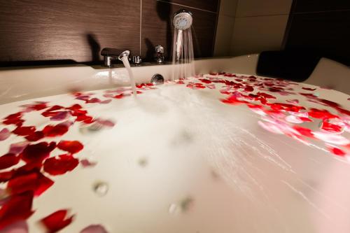 a bathroom sink with red rose petals on it at Lavender Inn Permas Jaya in Johor Bahru