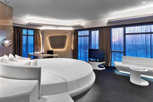 1 dormitorio con 1 cama blanca grande y TV en V Hotel Dubai, Curio Collection by Hilton, en Dubái